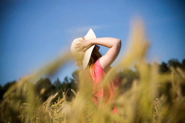 Giovane ragazza in un campo di grano in una soleggiata giornata estiva, segale dorata e cielo blu