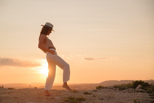 Giovane ragazza in vacanza balla al tramonto