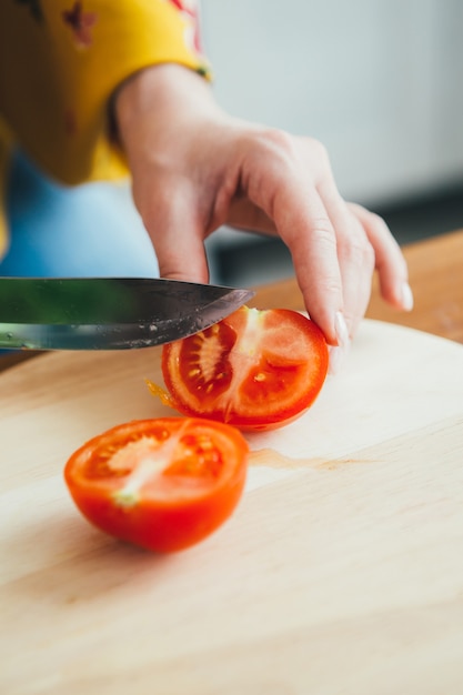 Giovane ragazza incinta carina che prepara insalata di verdure in cucina