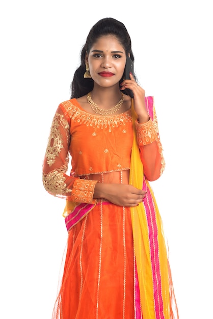 Giovane ragazza indiana tradizionale utilizzando un telefono cellulare o uno smartphone su bianco