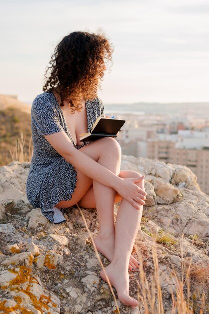 Giovane ragazza innamorata scrive nel suo taccuino pensieri all'aperto