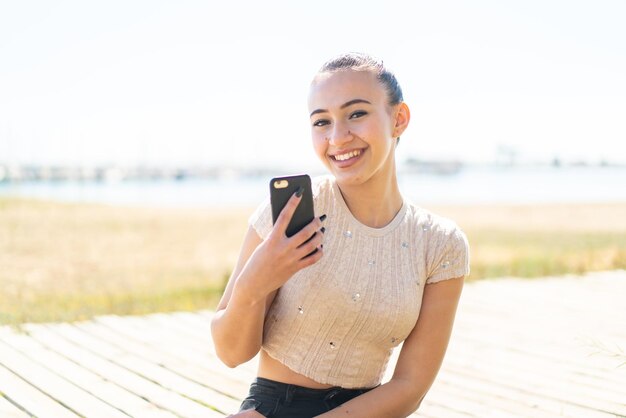 Giovane ragazza marocchina all'aperto in possesso di un telefono cellulare e con le braccia incrociate