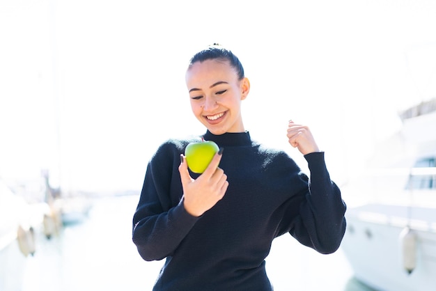 Giovane ragazza marocchina con una mela all'aperto che celebra una vittoria