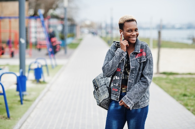 Giovane ragazza millenaria afroamericana in città. Donna di colore felice con gli auricolari senza fili. Concetto di generazione Z.