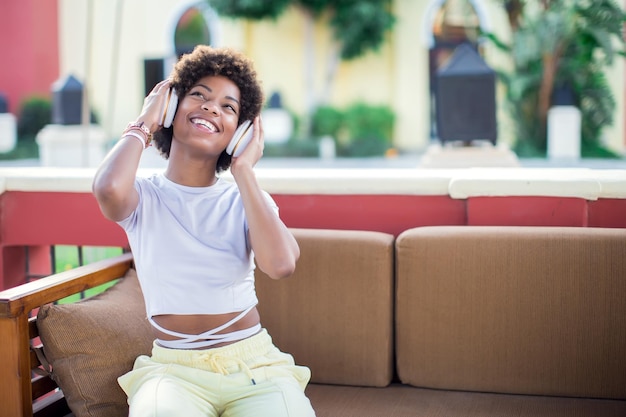 Giovane ragazza nera che ascolta la musica con le cuffie Concetto di stile di vita