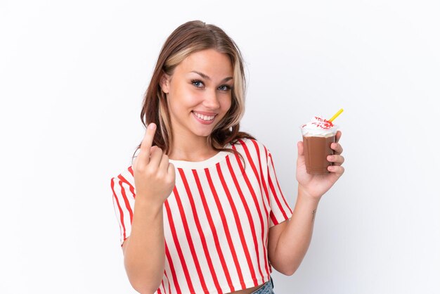 Giovane ragazza russa che tiene cappuccino isolato su sfondo bianco facendo il gesto in arrivo