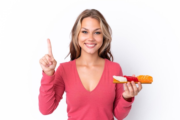 Giovane ragazza russa che tiene sashimi isolato su sfondo bianco che mostra e alza un dito in segno di meglio