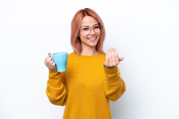 Giovane ragazza russa che tiene una tazza di caffè isolata su sfondo bianco che invita a venire con la mano Felice che tu sia venuto