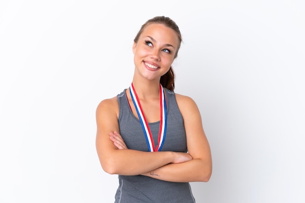 Giovane ragazza russa sportiva con medaglie isolate su sfondo bianco, alzando lo sguardo mentre sorride