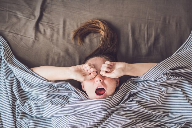 Giovane ragazza sdraiata a letto sotto una coperta