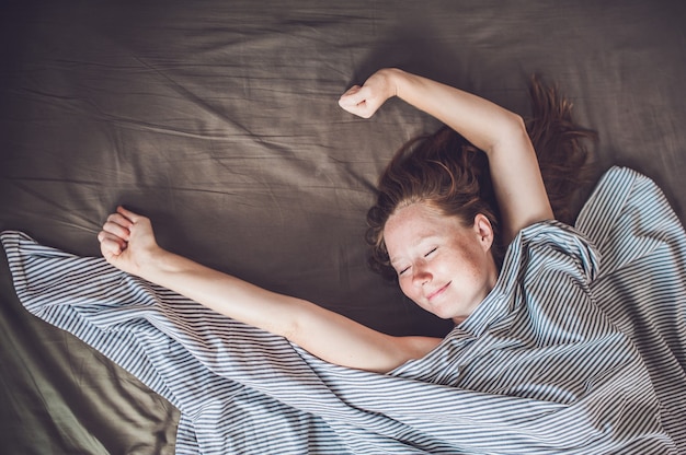 Giovane ragazza sdraiata a letto sotto una coperta