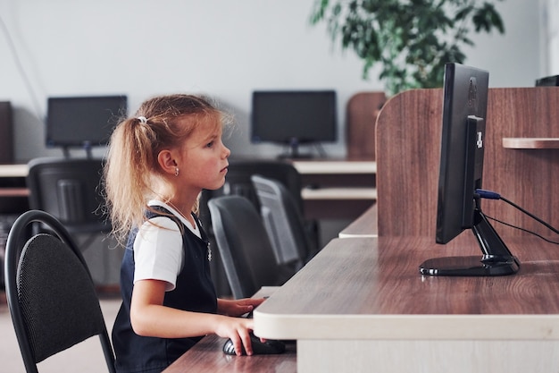 Giovane ragazza seduta al computer e alla ricerca di informazioni