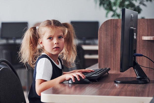 Giovane ragazza seduta al computer e alla ricerca di informazioni