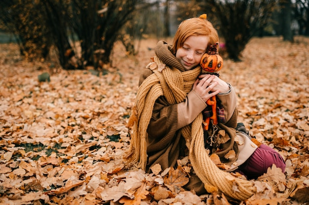Giovane ragazza seduta nel parco in autunno con il giocattolo