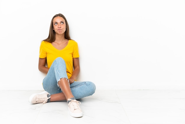 Giovane ragazza seduta sul pavimento e alzando lo sguardo