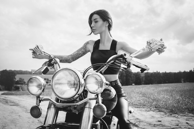 Giovane ragazza sexy in posa su una moto al tramonto. concetto di sport motoristico. Tecnica mista