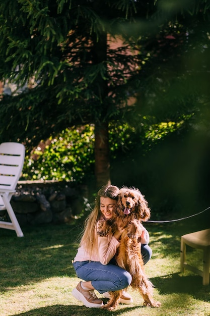 Giovane ragazza sorridente che abbraccia il suo cane sull'erba verde