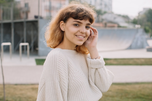 Giovane ragazza sorridente dei latinos con capelli ricci lunghi mentre stando da solo su una via.