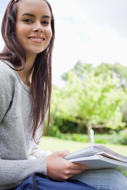 Giovane ragazza sorridente guardando la telecamera mentre si fa i compiti