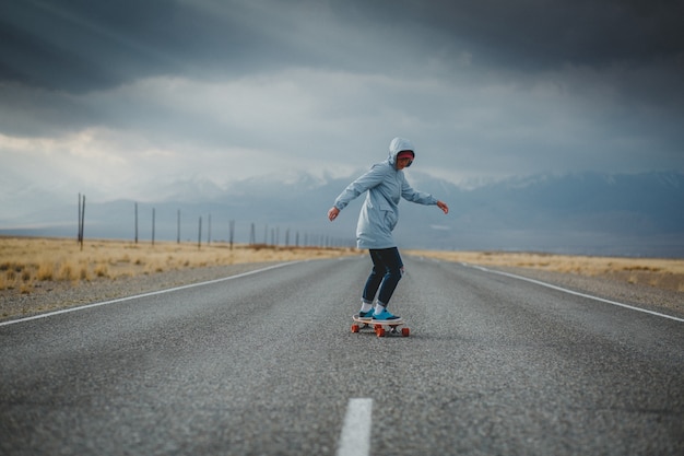 Giovane ragazza sportiva con longboard è in piedi su una strada deserta