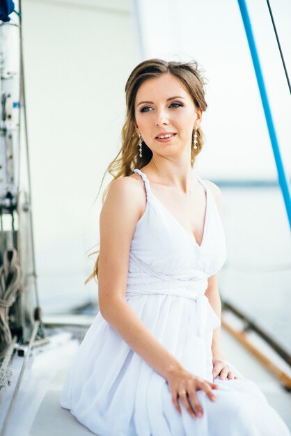 Giovane ragazza sul ponte di una barca a vela in legno bianco