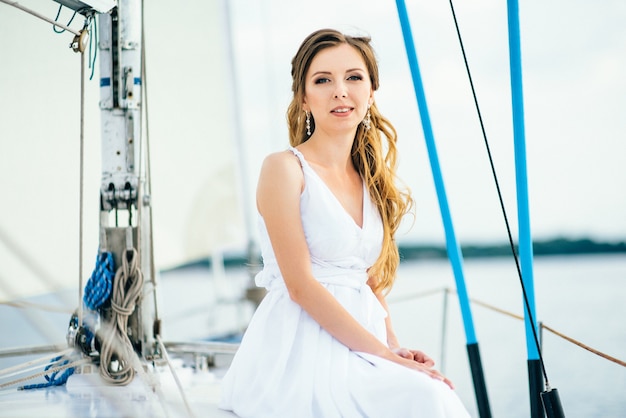 Giovane ragazza sul ponte di una barca a vela in legno bianco