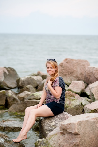 Giovane ragazza sulle rocce nel mare