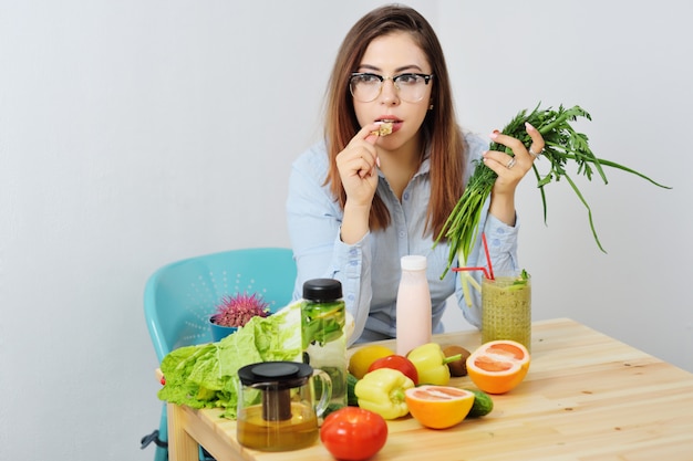 Giovane ragazza sveglia che mangia pane con fibra sulla superficie delle verdure.