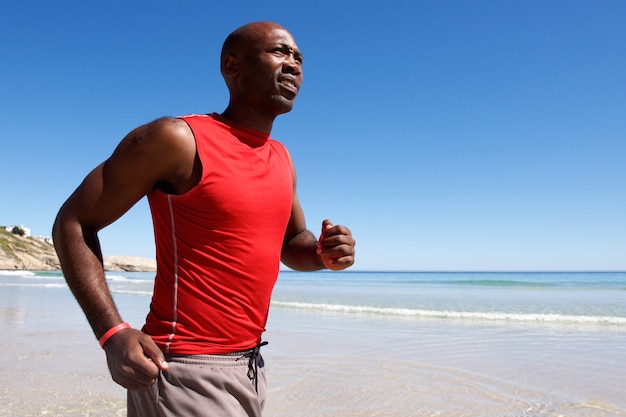 Giovane ragazzo africano in buona salute che funziona lungo la spiaggia