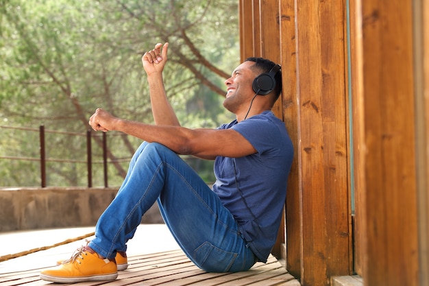 Giovane ragazzo africano seduto fuori e ascoltare musica