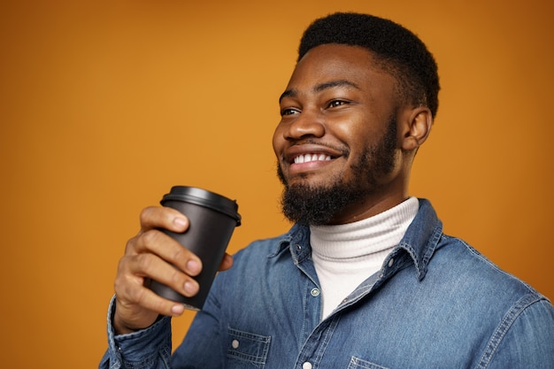 Giovane ragazzo afroamericano che gode della sua tazza di caffè da asporto contro