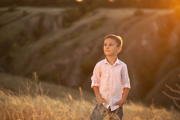 Giovane ragazzo alla moda che posa nel campo al tramonto