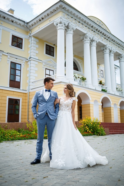 Giovane ragazzo alla moda in un vestito lo sposo e la sposa bella ragazza in un vestito bianco con un treno a piedi nel parco il giorno delle nozze