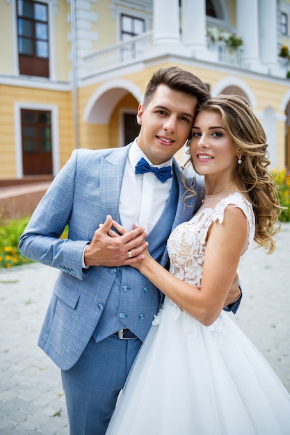 Giovane ragazzo alla moda in un vestito lo sposo e la sposa bella ragazza in un vestito bianco con un treno a piedi nel parco il giorno delle nozze