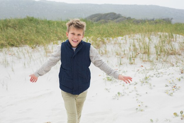 Giovane ragazzo allegro che funziona alla spiaggia