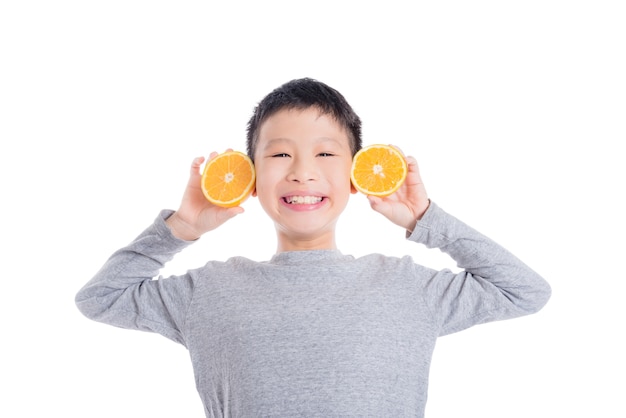 Giovane ragazzo asiatico che tiene arancia e sorride