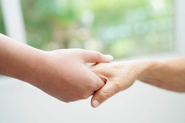 Giovane ragazzo asiatico che tiene la mano della nonna anziana insieme con amore e cura