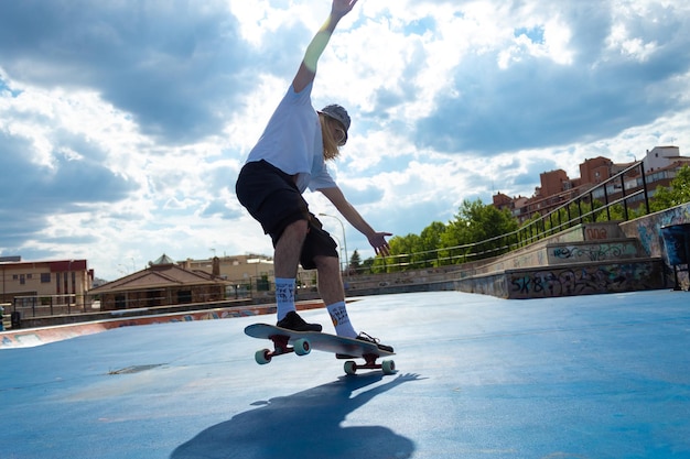 Giovane ragazzo biondo che esegue acrobazie con lo skateboard saltando nello skatepark