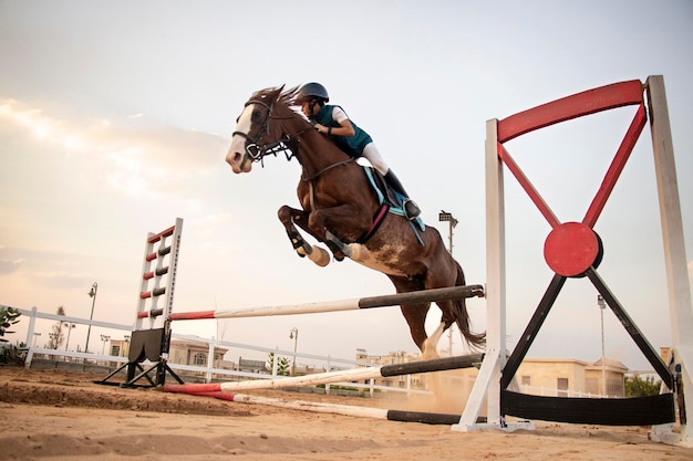 Giovane ragazzo cavaliere a cavallo che salta sopra un recinto in una corsa equestre