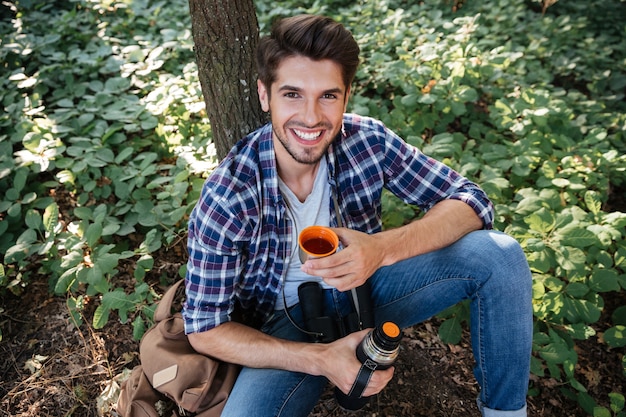 Giovane ragazzo che beve il tè nella foresta