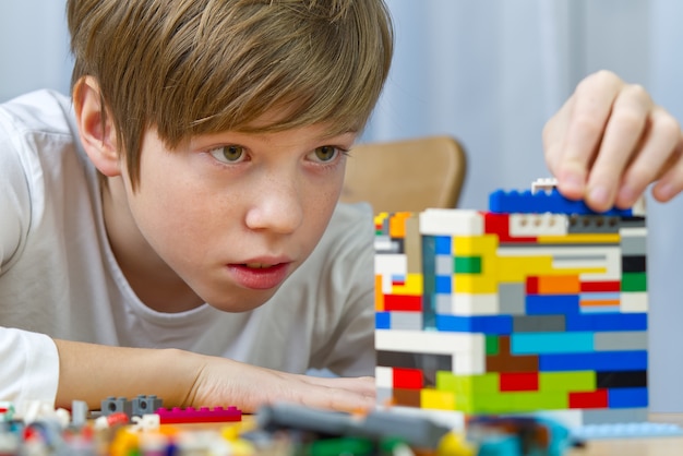 giovane ragazzo che gioca con i giocattoli di costruzione in plastica a casa.