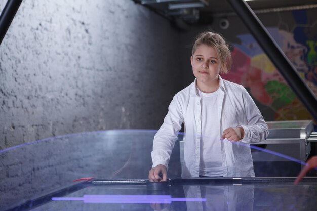 Giovane ragazzo che gioca lo spazio della copia di air hockey