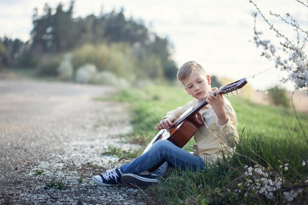 Giovane ragazzo che gioca sulla chitarra all'aperto