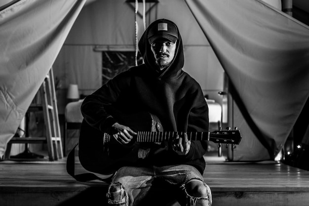 Giovane ragazzo che suona la chitarra acustica in natura alla sera