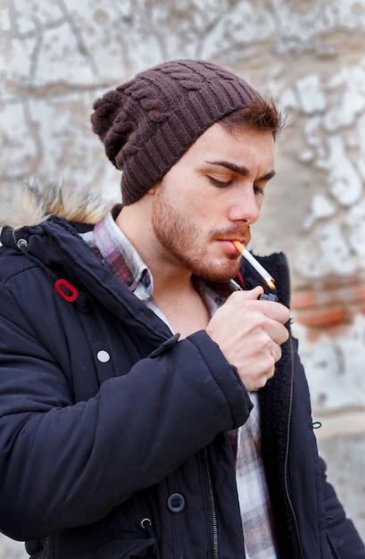 Giovane ragazzo con il fumo di berretto di lana