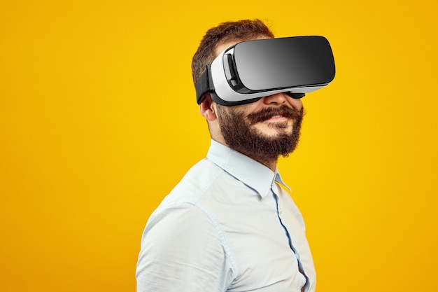 Giovane ragazzo con la barba in un moderno auricolare vr che sperimenta un altro mondo in studio