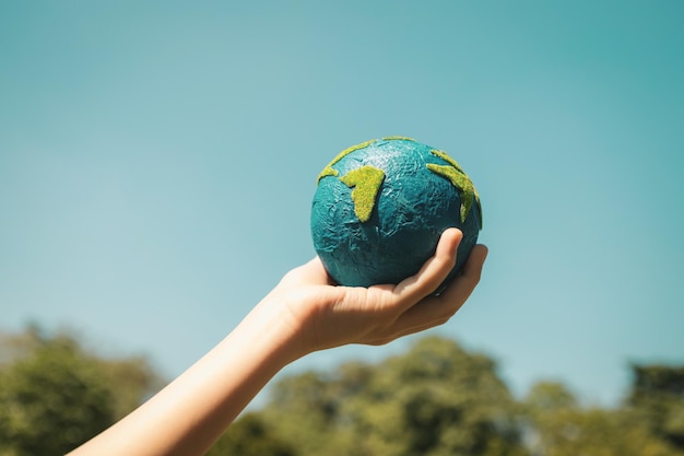 Giovane ragazzo con la mano che tiene il globo del pianeta terra con il giro di sfondo del cielo