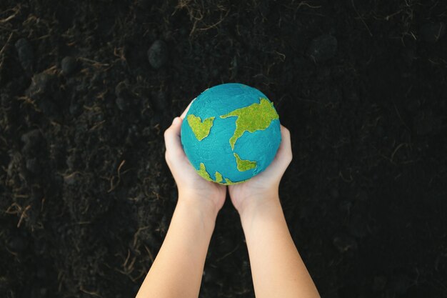 Giovane ragazzo con la mano che tiene il globo del pianeta Terra sullo sfondo del parco naturale Gyre