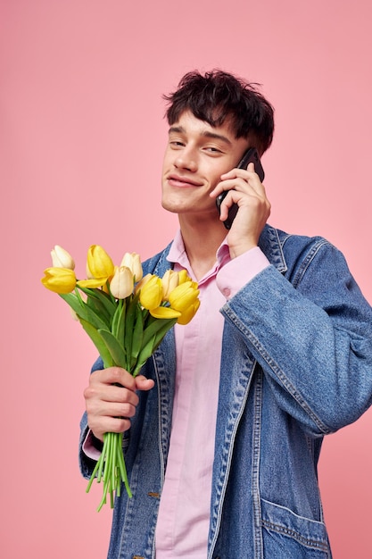 Giovane ragazzo con un mazzo di fiori che parla sul regalo della data del telefono