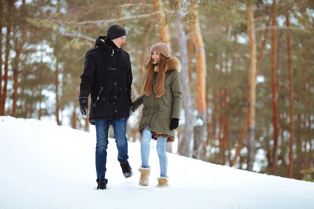 Giovane ragazzo e ragazza in abiti invernali che si godono la neve nella foresta